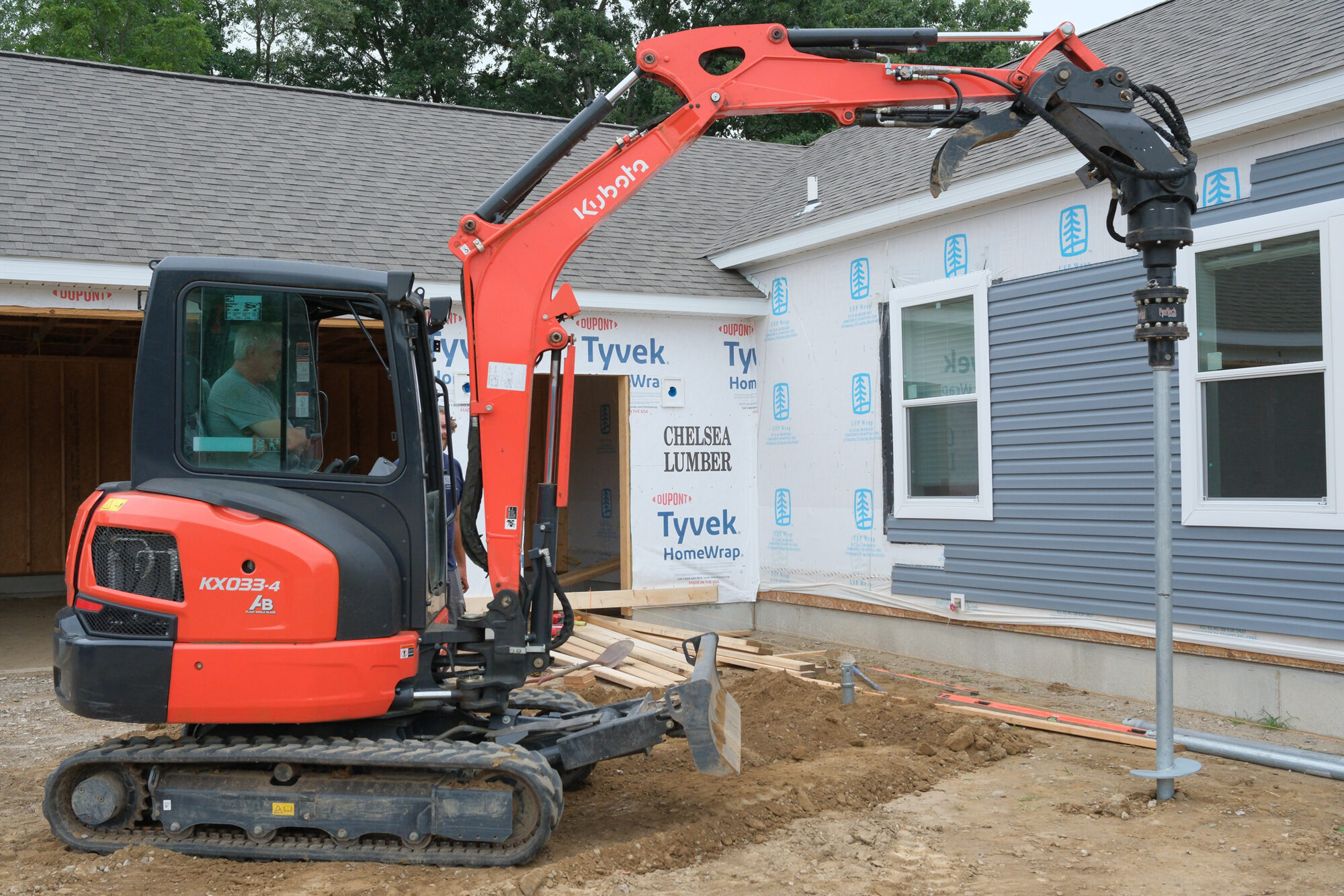 John Maguire, owner, driving a helical pier beside a new house with a mini excavator